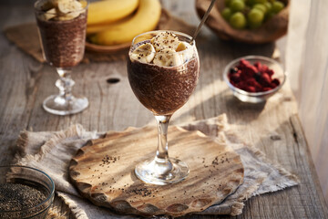 A cup of healthy chia chocolate pudding with banana slices and fresh fruit