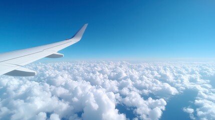 Fototapeta premium Airplane wing above fluffy white clouds against a vibrant blue sky, aerial view, daytime
