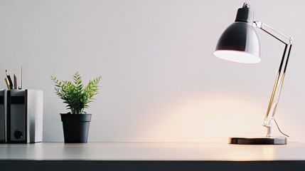 A minimalist desk setup with a small potted pothos plant beside a lamp.