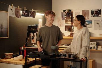 Portrait of smiling teenage girl and boy discussing film development process while working on...