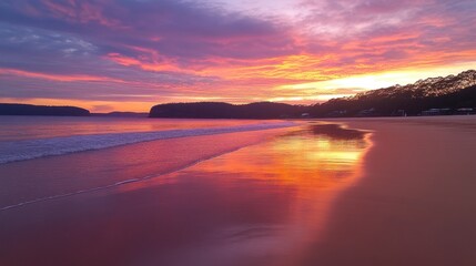 Fototapeta premium Stunning sunset over a quiet beach with golden sand, reflecting vibrant hues of orange, pink, and purple across the sky and water