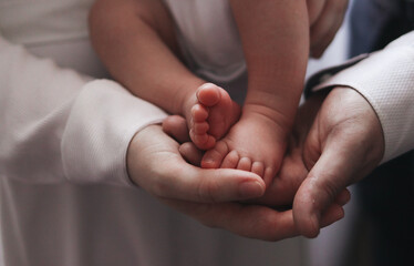 parents' hands gently hold the tiny feet of a baby. concept of care, protection and love. family warmth, trust. High quality photo
