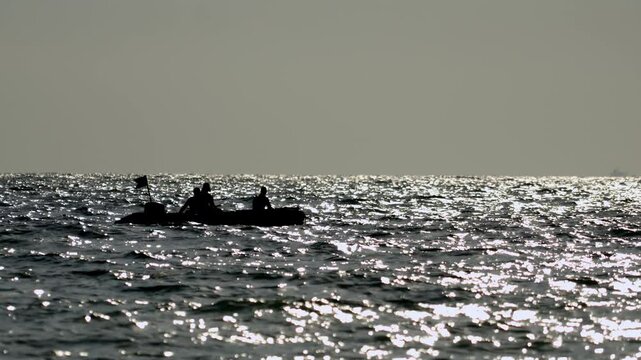 pirates on inflatable boat in high seas or ocean. Silhouettes of sinister, unrecognizable Somali pirates.