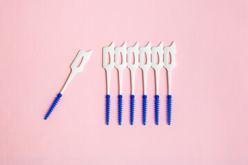 Brushes for cleaning the interdental spaces with rubber blue bristles on a pink background....