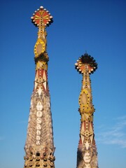 Close-up of two Sagrada Familia tower tops against clear blue sky. Architectural design details of Holy Family church towers. Detailed Sagrada Familia ornate spires. Landmark of Barcelona, Spain