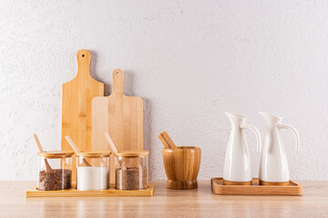 A beautiful storage area for spices in glass jars and oils in ceramic special bottles on a wooden countertop in the kitchen space. Eco style.