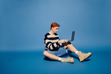 Young man sitting on the floor engaged in deep thought while using a laptop