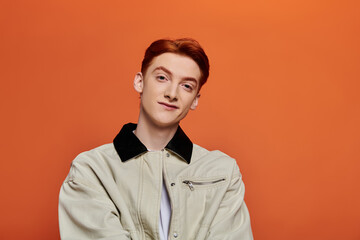 Young man with vibrant expression poses against a striking orange background
