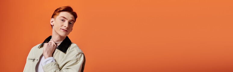 Charming young man with striking expression against vibrant orange backdrop