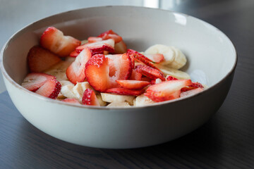 white ceramic bowl full of strawberry and banana slices close-up