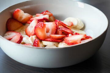 white ceramic bowl full of strawberry and banana slices close-up