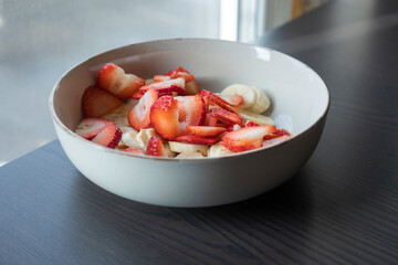 white ceramic bowl full of strawberry and banana slices close-up