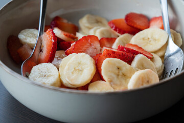 white ceramic bowl full of strawberry and banana slices close-up
