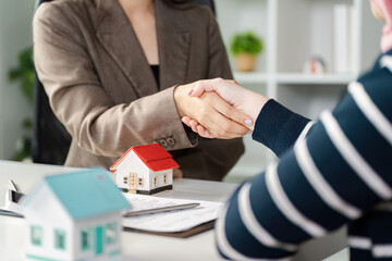 Real estate agent shaking hands with a client, finalizing a property deal and discussing investment opportunities.
