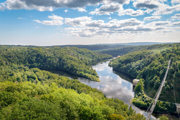 Rappbode Valley, Germany  – August 26, 2024: Tourists visit the Titan RT Suspension bridge at the Rappbode Dam (Harz Mountains, Saxony). It spans the river Bode in the middle of the valley