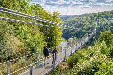 Rappbode Valley, Germany  – August 26, 2024: Tourists visit the Titan RT Suspension bridge at the Rappbode Dam (Harz Mountains, Saxony). It spans the river Bode in the middle of the valley
