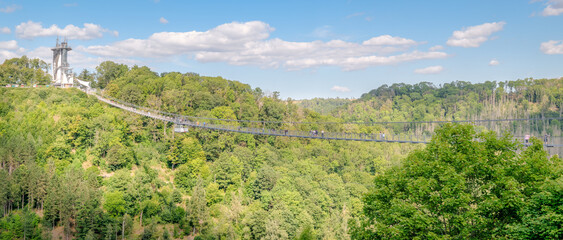 Rappbode Valley, Germany  – August 26, 2024: Tourists visit the Titan RT Suspension bridge at the Rappbode Dam (Harz Mountains, Saxony). It spans the river Bode in the middle of the valley