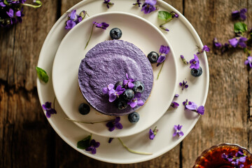 Vegan raw blueberry cheesecake. Wooden background, viola, blueberry 