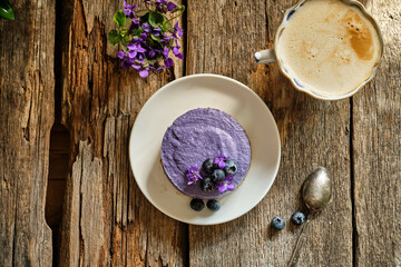 Vegan raw blueberry cheesecake. Wooden background, viola, blueberry 