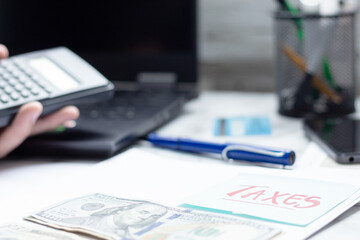 Calculator, documents, banknotes and sticky note with text Taxes, on an office desk. Personal...