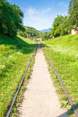 Obraz premium old railroad passes through the valley. mountainous countryside in morning light. sunny weather with blue sky and clouds. outdoor adventure in western ukraine