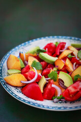 Fresh spring salad witn avocado, tomato, peach, red onion and herbs
