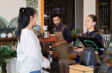 Asian cafe cashier worker female showing menu or cashless billing payment to customer, barista...
