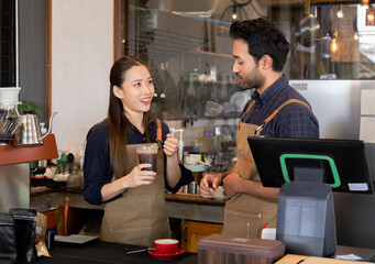 Cafe staff discussing behind counter with coffee machine. Female barista holding iced coffee, Indian male startup eatery shop owner preparing hot drink. small business entrepreneur coffee shop
