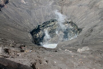 Dramatic aerial view of volcanic crater with steam rising, showcasing raw power and geological...