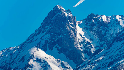 Detailed megazoom (600mm) summer view of a mountain summit and a passing by jet airplane seen from...