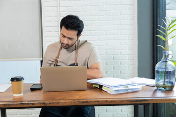 Fototapeta premium Attractive barista male or employee concentrate on stacks of tax declaration bills, restaurant owner using laptop for bookkeeping control payment, multitask small business lifestyle doing everything