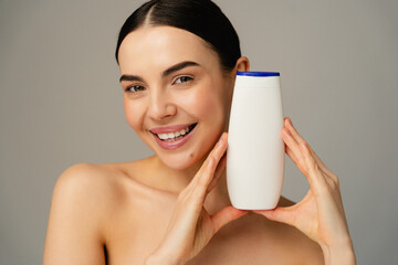 Youthful joy is expressed as a cheerful girl holds a bottle of personal care product. Conveys beauty, health, happiness, and a passion for wellness, with neutral tones accentuating natural elegance.