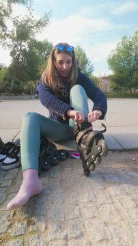 Young woman putting on inline skates in a park
