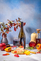 Autumn still life with wine, cheese, and seasonal fruits displaying warm colors