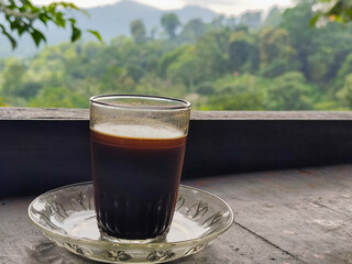 A cup of coffee in the highlands, with beautiful and fresh mountain views in the background.