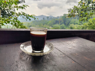 A cup of coffee in the highlands, with beautiful and fresh mountain views in the background.