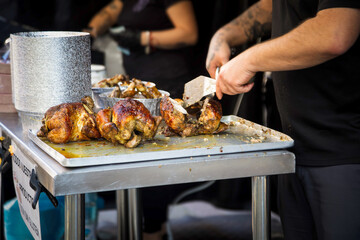 Man cutting chickens at a street roast chicken stall