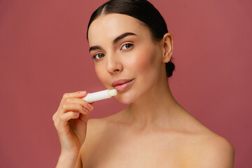 Close-up depicting a person applying lip balm, highlighting skincare and natural beauty against a...