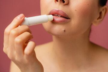 Detailed close-up view of a person using lip balm with a gentle touch. Depicts skincare, hydration,...