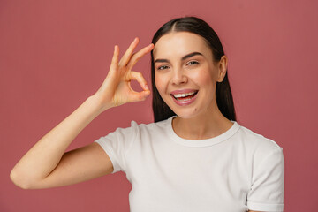 Smiling individual wearing casual attire makes an approval sign, conveying positive vibes and...