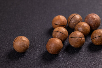 Macadamia nuts resting on a dark surface