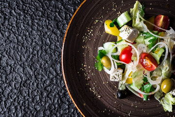 Greek Salad with Feta in plate on black background.. High quality photo.