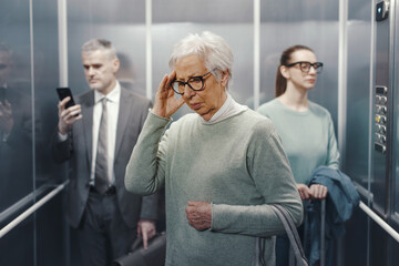 Confused senior lady with headache standing inside the elevator © stokkete