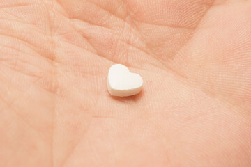 The medical concept of diseases of the human cardiovascular system. Heart-shaped pills on a person's arm. 