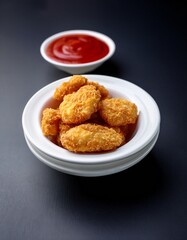 Fotografía de estudio profesional una fuente de nuggets de pollo casero crujientes, acompañados de un tazón blanco de vibrante salsa marinera roja, estilo ultrarrealista, realista, 4k