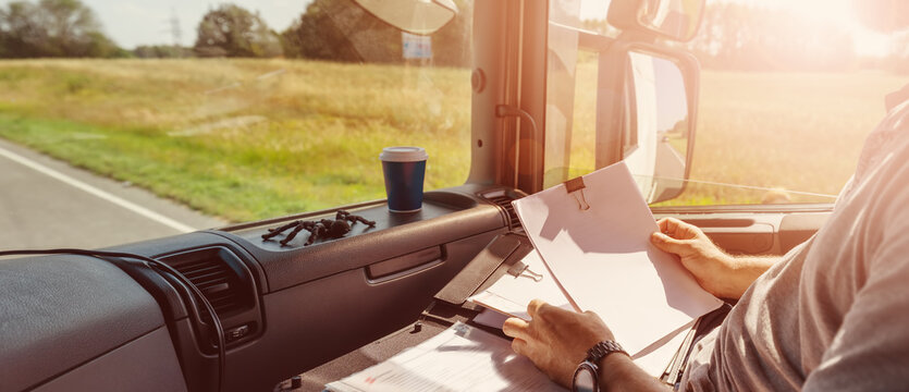 Truck driver sitting in the car and writing documents.
