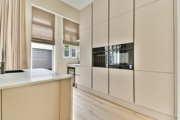 Sleek and sophisticated kitchen featuring beige cabinetry and natural light, embodying a minimalist aesthetic and contemporary functionality.