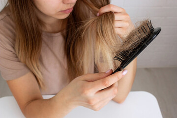 Naklejka premium The woman holds a hair brush and vitamins from hair loss. Selective focus