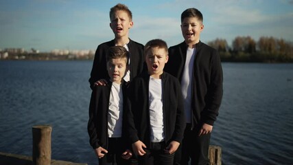 Quartet of boys singing by the lake. Concept of vocal singing.