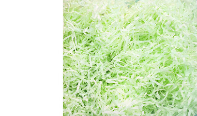 Close-up view of crinkle-cut shredded paper in soft green tones, commonly used as protective filler for packaging and gifts